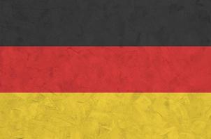 Germany flag depicted in bright paint colors on old relief plastering wall. Textured banner on rough background photo