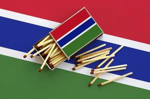 Gambia flag  is shown on an open matchbox, from which several matches fall and lies on a large flag photo