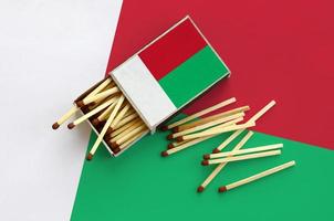 Madagascar flag  is shown on an open matchbox, from which several matches fall and lies on a large flag photo