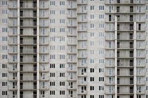 Textured pattern of a russian whitestone residential house building wall with many windows and balcony under construction photo