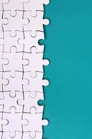 Fragment of a folded white jigsaw puzzle on the background of a blue plastic surface. Texture photo with copy space for text