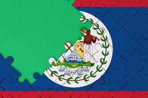 Belize flag  is depicted on a completed jigsaw puzzle with free green copy space on the left side photo