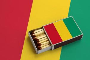 Guinea flag  is shown in an open matchbox, which is filled with matches and lies on a large flag photo