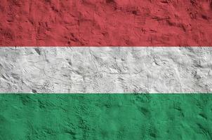 Hungary flag depicted in bright paint colors on old relief plastering wall. Textured banner on rough background photo