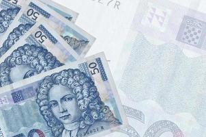 50 Croatian kuna bills lies in stack on background of big semi-transparent banknote. Abstract business background photo