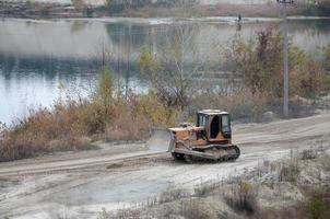 agregado de cantera con maquinaria pesada. Excavadora de oruga con retroexcavadora que conduce a la cantera del sitio de construcción foto