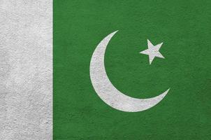 Pakistan flag depicted in bright paint colors on old relief plastering wall. Textured banner on rough background photo