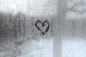 The heart is painted on the misted glass in winter photo