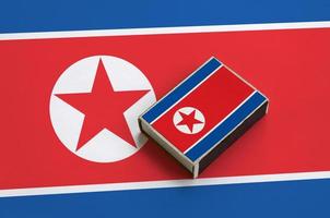 North Korea flag  is pictured on a matchbox that lies on a large flag photo