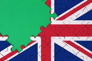 Great britain flag  is depicted on a completed jigsaw puzzle with free green copy space on the left side photo