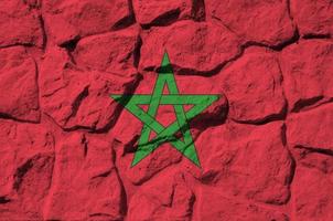 bandera de marruecos representada en colores de pintura en el primer plano de la pared de piedra antigua. banner texturizado sobre fondo de pared de roca foto