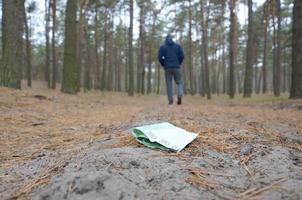 Young man loses his euro money bills on Russian autumn fir wood path. Carelessness and losing money concept photo