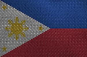 Philippines flag depicted in paint colors on old brushed metal plate or wall closeup. Textured banner on rough background photo