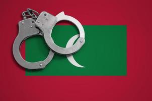 Maldives flag  and police handcuffs. The concept of crime and offenses in the country photo