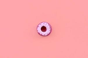 Single small plastic donut lies on a pastel colorful background. Flat lay minimal composition. Top view photo