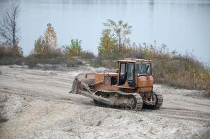 Quarry aggregate with heavy duty machinery. Caterpillar loader Excavator with backhoe driving to construction site quarry photo