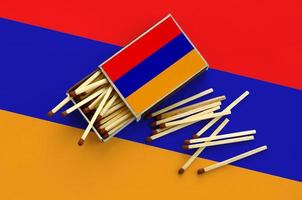 Armenia flag  is shown on an open matchbox, from which several matches fall and lies on a large flag photo