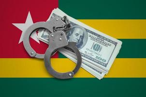 Togo flag  with handcuffs and a bundle of dollars. Currency corruption in the country. Financial crimes photo