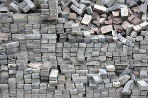 A large pile of disassembled paving slabs. A lot of square stones before the reconstruction of the pavement site photo