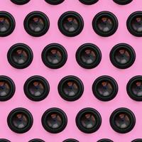 A few camera lenses with a closed aperture lie on texture background of fashion pastel pink color paper in minimal concept. Abstract trendy pattern photo