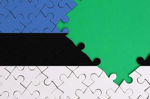 Estonia flag  is depicted on a completed jigsaw puzzle with free green copy space on the right side photo