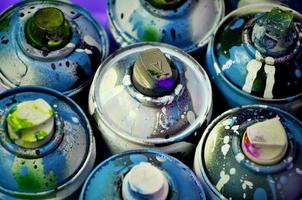 Bodegón con un gran número de latas de aerosol de colores usadas sobre la superficie de madera tratada en el taller de graffiti del artista. latas sucias y manchadas para spray art foto