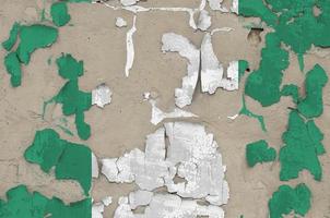 Nigeria flag depicted in paint colors on old obsolete messy concrete wall closeup. Textured banner on rough background photo