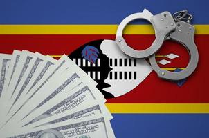 Swaziland flag  with handcuffs and a bundle of dollars. The concept of illegal banking operations in US currency photo