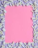 Colorful marshmallow laid out on violet and pink paper background. pastel creative textured framework. minimal photo