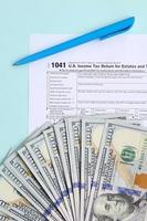 1041 tax form lies near hundred dollar bills and blue pen on a light blue background. US Income tax return for estates and trusts photo