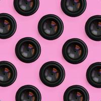 A few camera lenses with a closed aperture lie on texture background of fashion pastel pink color paper in minimal concept. Abstract trendy pattern photo