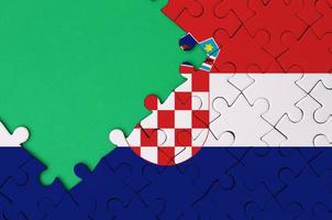 Croatia flag  is depicted on a completed jigsaw puzzle with free green copy space on the left side photo