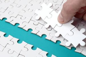The human hand paves the way to the surface of the jigsaw puzzle, forming a blue space. The concept of overcoming the difficulties on the way to success photo