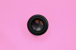 Camera lens with a closed aperture lie on texture background of fashion pastel pink color paper in minimal concept photo