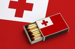 Tonga flag  is shown in an open matchbox, which is filled with matches and lies on a large flag photo