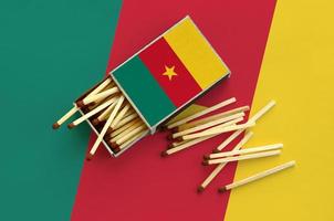 Cameroon flag  is shown on an open matchbox, from which several matches fall and lies on a large flag photo