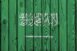 Saudi Arabia flag depicted in bright paint colors on old wooden wall. Textured banner on rough background photo