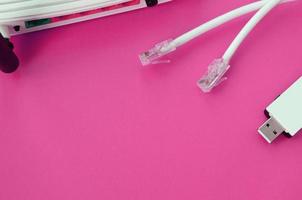 Internet router, portable USB wi-fi adapter and internet cable plugs lie on a bright pink background. Items required for internet photo