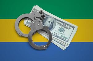 Gabon flag  with handcuffs and a bundle of dollars. Currency corruption in the country. Financial crimes photo