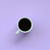 Small white coffee cup on texture background of fashion pastel violet color paper in minimal concept photo