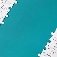Fragment of a folded white jigsaw puzzle on the background of a blue plastic surface. Texture photo with copy space for text