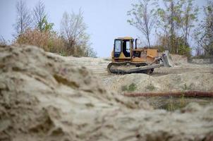 Quarry aggregate with heavy duty machinery. Caterpillar loader Excavator with backhoe driving to construction site quarry photo