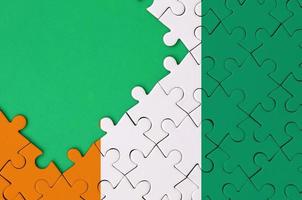 Ivory Coast flag  is depicted on a completed jigsaw puzzle with free green copy space on the left side photo