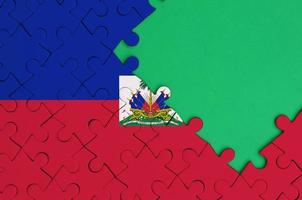 Haiti flag  is depicted on a completed jigsaw puzzle with free green copy space on the right side photo