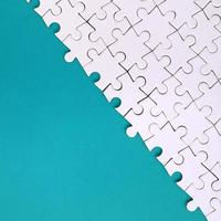 Fragment of a folded white jigsaw puzzle on the background of a blue plastic surface. Texture photo with copy space for text