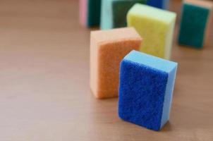 A few kitchen sponges lie on a wooden kitchen countertop. Colorful objects for washing dishes and cleaning in the house are ready for use photo