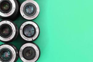 Several photographic lenses lie on a bright turquoise background. Copy space photo