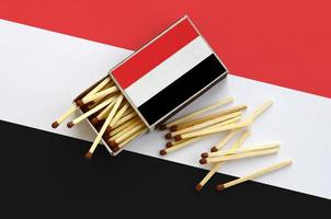 Yemen flag  is shown on an open matchbox, from which several matches fall and lies on a large flag photo