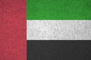 United Arab Emirates flag depicted in bright paint colors on old relief plastering wall. Textured banner on rough background photo