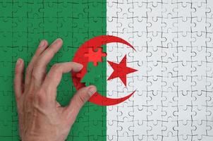 Algeria flag  is depicted on a puzzle, which the man's hand completes to fold photo